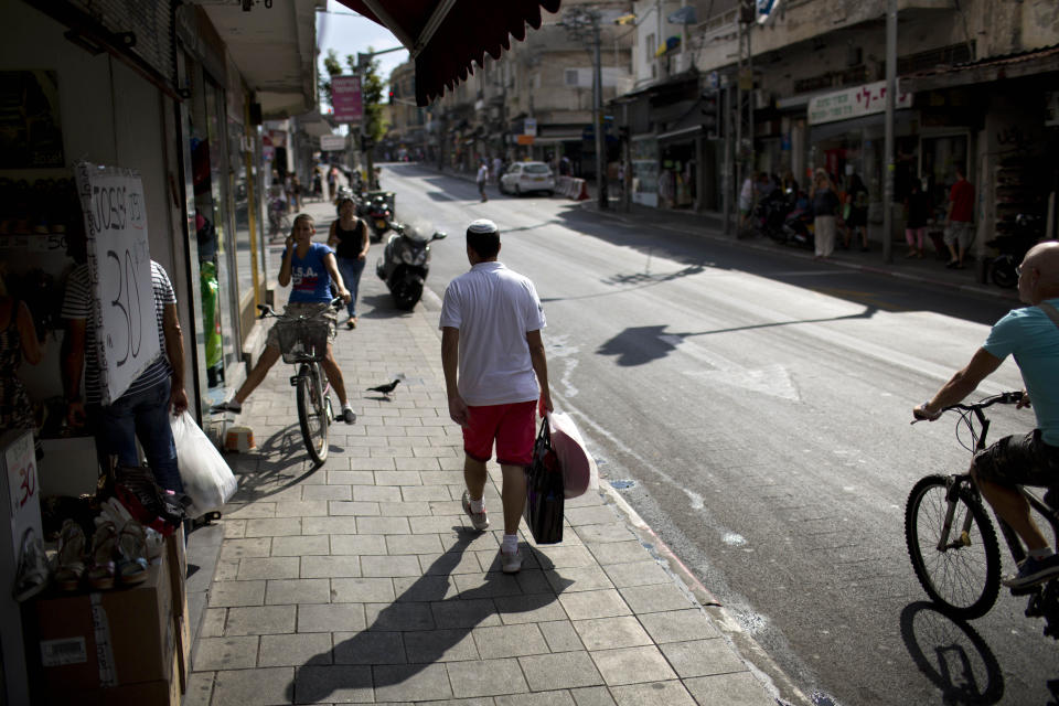 In this photo taken on Thursday, July 25, 2013, Israeli Orthodox Shahar Hadar carries women's clothing he bought for his next show, in downtown Tel Aviv, Israel. Hadar, a telemarketer by day, has taken the gay Orthodox struggle from the synagogue to the stage, beginning to perform as one of Israel’s few religious drag queens. His drag persona is that of a rebbetzin, a female rabbinic advisor, a wholesome guise that stands out among the sarcastic and raunchy cast of characters on Israel’s drag queen circuit. (AP Photo/Oded Balilty)