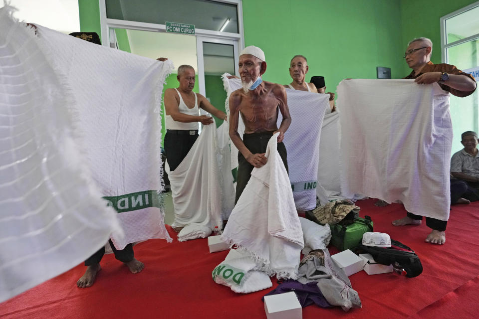 Husin bin Nisan, center, with other worshippers, prepares to wear a special garb called "ihram," typically worn during hajj pilgrimage, prior to a hajj rehearsal in Tangerang, Indonesia, Monday, May 15, 2023. After spending more than three decades picking tips from motorists, the 85-year-old volunteer traffic attendant is finally realizing his dream to go to the Islamic holy cities of Mecca and Medina for hajj pilgrimage. (AP Photo/Achmad Ibrahim)