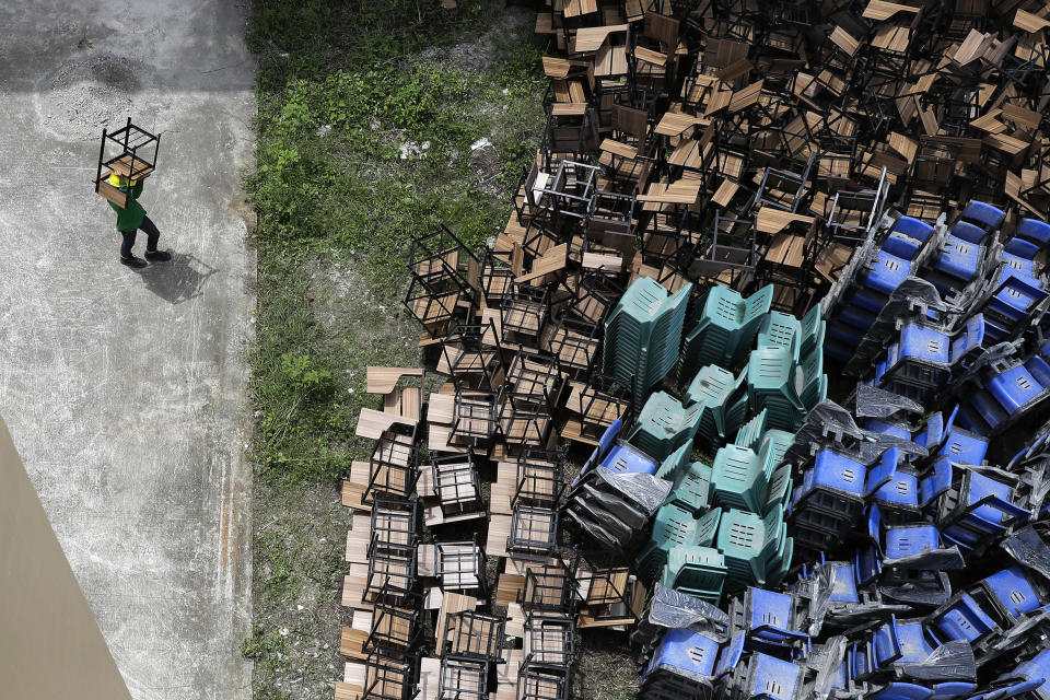 A worker arranges chairs as they temporarily convert a public school to a COVID-19 quarantine facility in Quezon city, Philippines on Tuesday, Sept. 1, 2020, as the government further eased lockdown restrictions despite the country having the most coronavirus infections in Southeast Asia. (AP Photo/Aaron Favila)