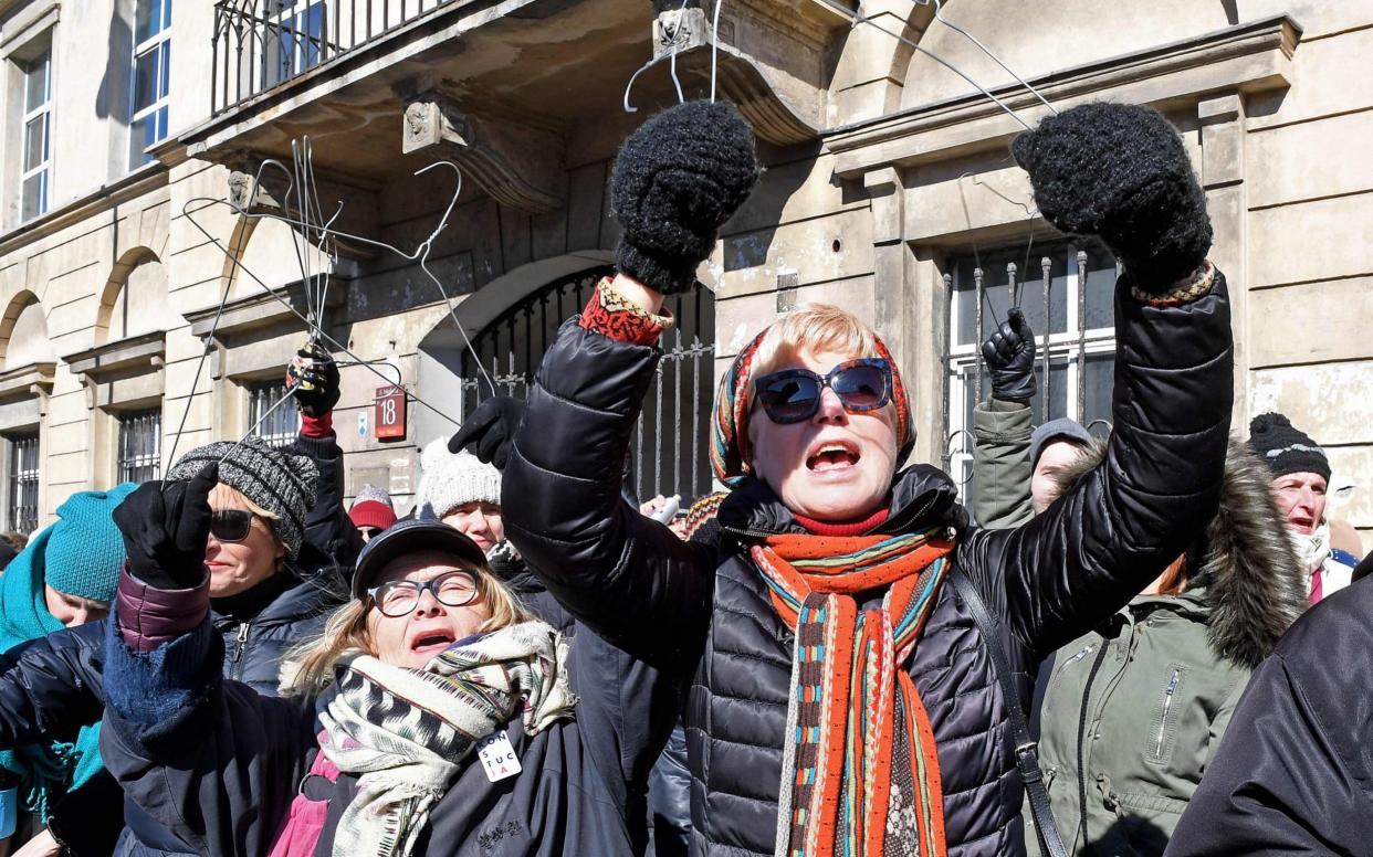 Women in Warsaw brandish coat hangers as they protest against laws to restrict abortion - AFP