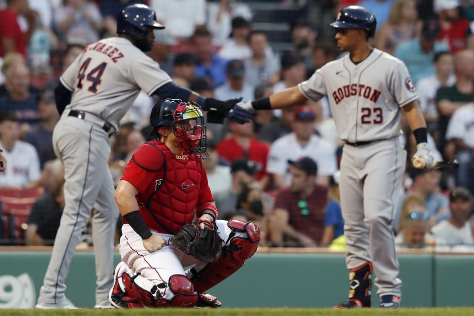 Boston Red Sox's Christian Vazquez, center, kneels at home plate as Houston Astros' Yordan Alvarez, left, celebrates with Michael Brantley, right, after scoring during the third inning of a baseball game, Wednesday, June 9, 2021, in Boston. (AP Photo/Michael Dwyer)