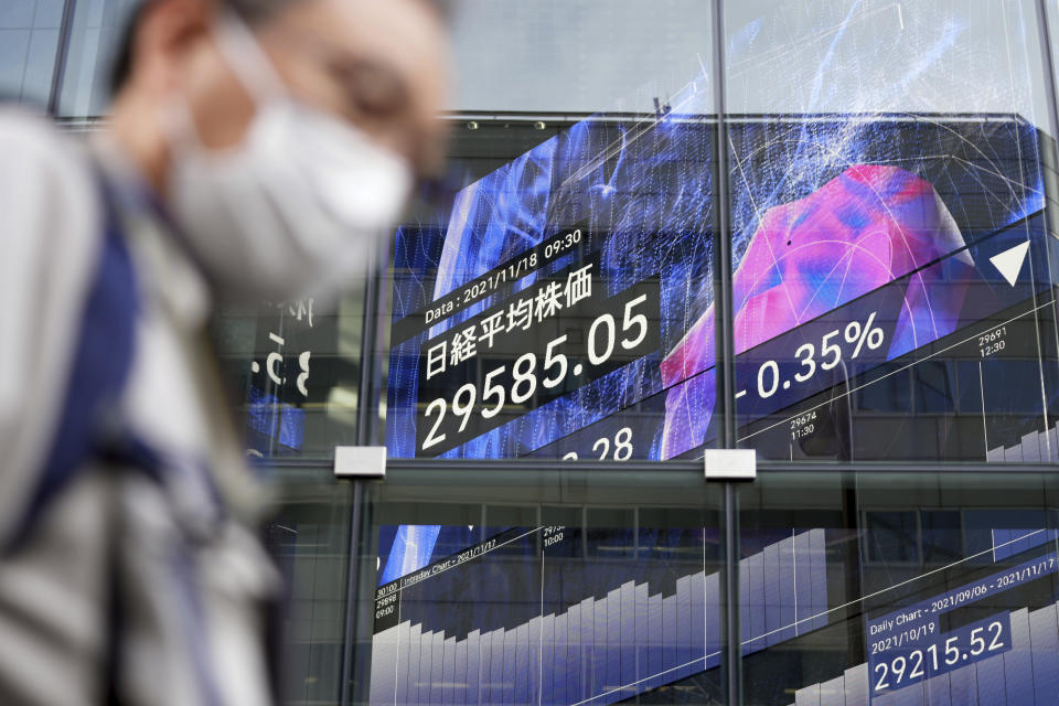 A man wearing a protective mask walks near an electronic stock board showing Japan's Nikkei 225 index at an exhibition hall Thursday, Nov. 18, 2021, in Tokyo. Asian shares mostly declined Thursday after stock indexes shuffled lower on Wall Street. (AP Photo/Eugene Hoshiko)