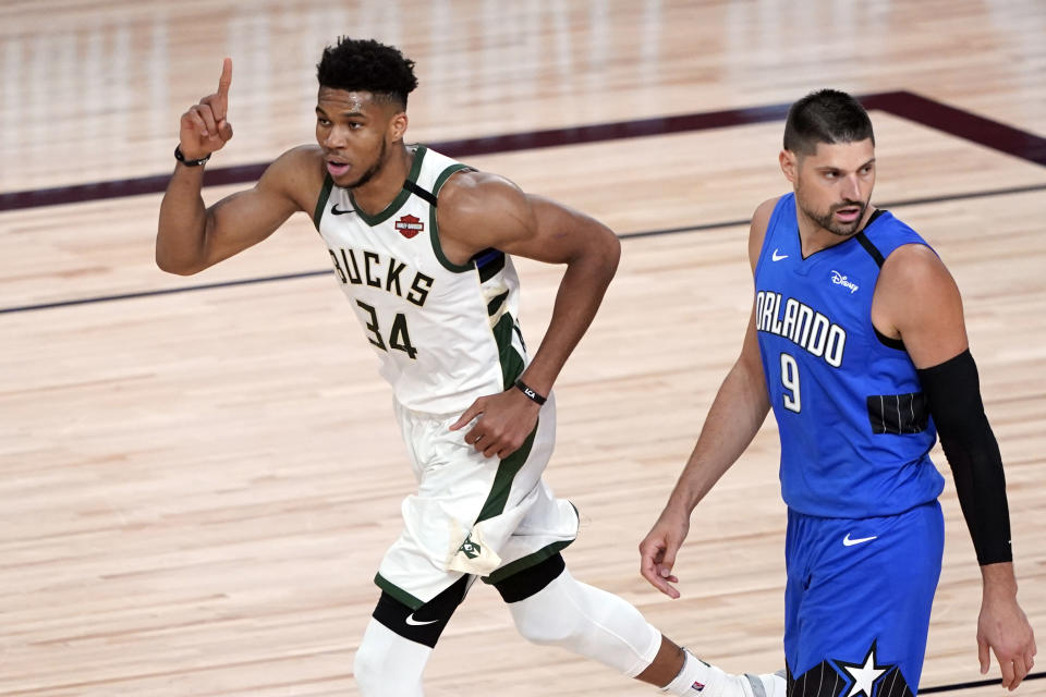 Milwaukee Bucks' Giannis Antetokounmpo (34) celebrates after a dunk as Orlando Magic's Nikola Vucevic (9) looks back during the first half of an NBA basketball first round playoff game Saturday, Aug. 29, 2020, in Lake Buena Vista, Fla. (AP Photo/Ashley Landis)