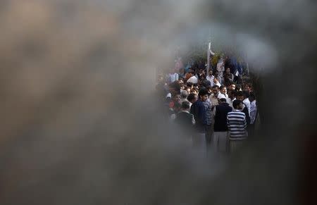 Kashmiri people are seen through a bullet hole on the window pane of a residential house after a gun battle on the outskirts of Srinagar, October 3, 2013. REUTERS/Danish Ismail/Files