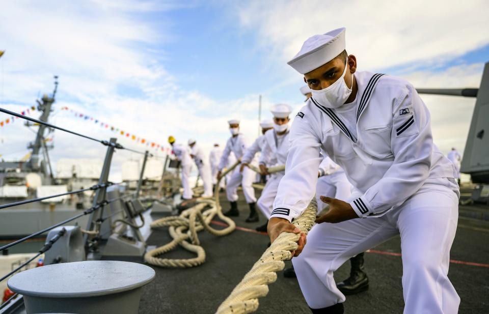In this image provided by the U.S. Navy, Seaman Apprentice Kyle Darden, from Warrenton, Va., heaves a mooring line as the guided-missile destroyer USS Michael Murphy (DDG 112) gets underway to render honors to Battleship Missouri Memorial and USS Arizona Memorial during the official ceremony for the 75th anniversary of the Japanese surrender that ended World War II, Wednesday, Sept. 2, 2020, in Honolulu, Hawaii. (Petty Officer 1st Class Devin Langer/U.S. Navy via AP)