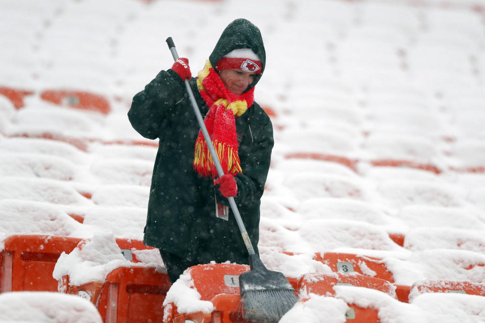 A groundskeeper brushes snow off of seats at Arrowhead Stadium before an NFL divisional football playoff game against the Indianapolis Colts in Kansas City, Mo., Saturday, Jan. 12, 2019. (AP Photo/Charlie Neibergall)