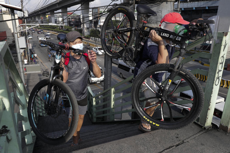 Men wearing protective masks carry their bicycles at an overpass in Quezon city, Philippines, Saturday, Sept. 26, 2020. Public transportation remains limited and the government orders commuters to wear face shields and face masks to help curb the spread of the coronavirus. (AP Photo/Aaron Favila)