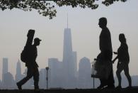 People walk past the skyline of New York's Lower Manhattan and One World Trade Center in a park along the Hudson River in Hoboken, New Jersey, September 11, 2013. Americans marked the 12th anniversary of the 9/11 attacks with solemn ceremonies and pledges not to forget the nearly 3,000 killed when hijacked jetliners crashed into the World Trade Center, the Pentagon and a Pennsylvania field, in 2001. REUTERS/Gary Hershorn