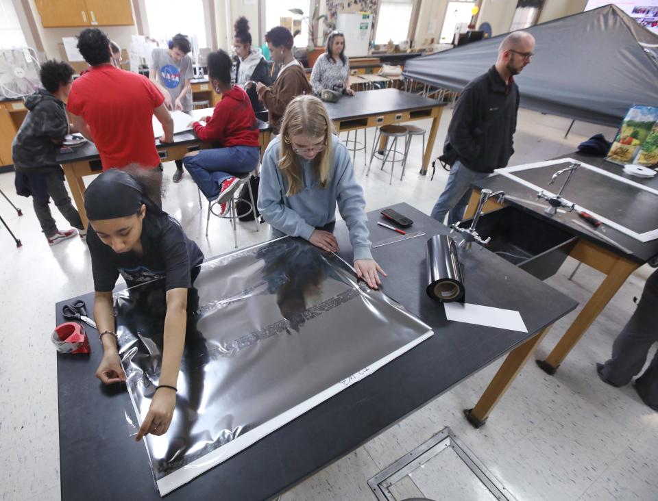 Kyeonie 'Keke' Leta-Robinson, tenth grade, and Miracle Galland, ninth grade, work together to tape down sheets of silver black polymer solar film to create a skylight for viewing the upcoming total solar eclipse, in science teacher Ellen Post's classroom at Wilson High School in Rochester Thursday, March 14, 2024.