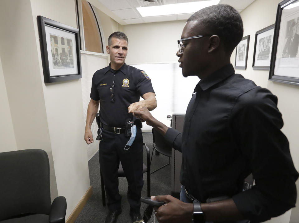 In this June 18, 2020 photo, demonstration organizer Weidmayer Pierre, right, fist bumps Palm Beach Police Capt. Joe Guelli after Guelli took him on a tour of sites that could accommodate an upcoming protest in Palm Beach, Fla. Before the death of George Floyd, business-management student Pierre had planned to spend his Florida summer break working at Wal-Mart. Instead, the 19-year-old has been organizing a protest every few days in Palm Beach County, determined to channel the groundswell of energy around the world into meaningful, peaceful reform in his hometown. (AP Photo/Wilfredo Lee)
