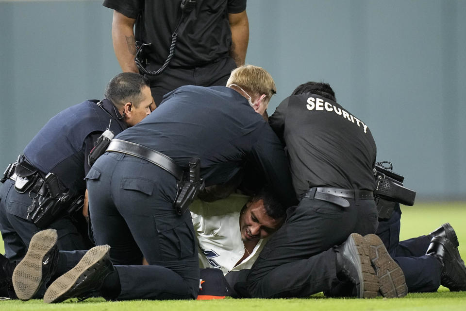 Security remove a fan on the field in between the eighth and ninth innings in Game 2 of baseball's American League Championship Series between the Houston Astros and the New York Yankees, Thursday, Oct. 20, 2022, in Houston. (AP Photo/Eric Gay)