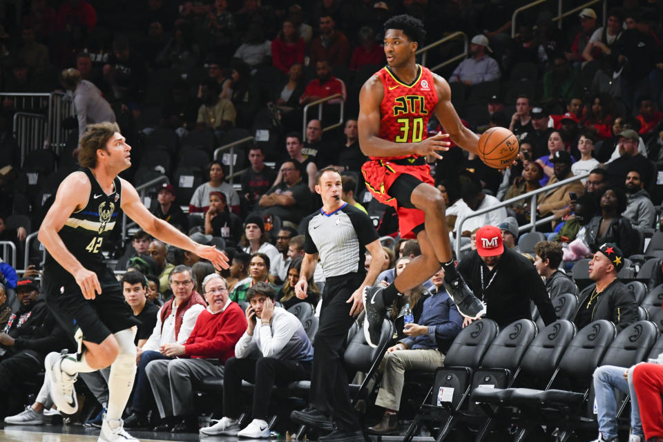 Atlanta Hawks center Damian Jones (30) saves a ball from going out of bounds as Milwaukee Bucks center Robin Lopez (42) defends during the second half of an NBA basketball game Friday, Dec. 27, 2019, in Atlanta. (AP Photo/John Amis)