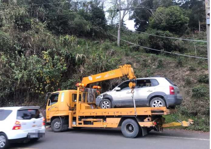 警方請來拖吊車協助將邊坡草叢內的翻車吊起載往修車廠。（圖／讀者提供）