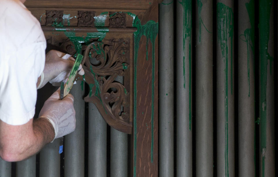 William Adair of Gold Leaf Studios removes green paint from the organ in the Washington National Cathedral's historic Bethlehem Chapel, Tuesday, July 30, 2013, in Washington. Officials at the cathedral discovered the paint inside two chapels Monday afternoon. The paint was splashed onto the organ and on the floor inside the Bethlehem Chapel on the basement level and inside Children's Chapel in the nave of the cathedral. (AP Photo/Carolyn Kaster)