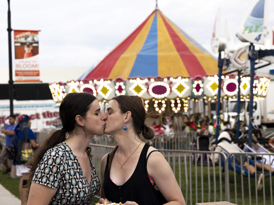 Rep. Zooey Zephyr and her fiancée Erin Reed kiss in between funnel cake at the Western Montana Fair in Missoula, Mont., on Aug. 9, 2023. (Rebecca Stumpf for NBC News)