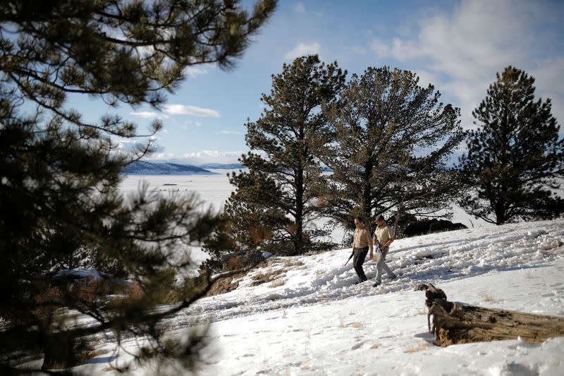 Drew Miller and Kacey Dawson walk across the property of a survival camp armed with weapons