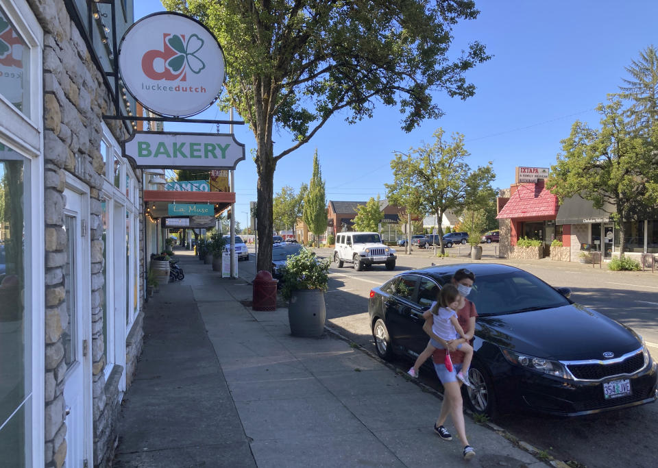 A woman and her child walk through downtown Newberg, Ore., on Tuesday, Sept. 21, 2021. The Chehalem Valley Chamber of Commerce told the school board that it has received numerous phone calls and emails from people saying they will boycott Newberg, the valley's main town, because of its ban on educators displaying Black Lives Matter and gay pride symbols in schools. (AP Photo/Andrew Selsky)