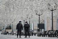 Russian law enforcement officers wearing protective masks stand guard in a street in Moscow