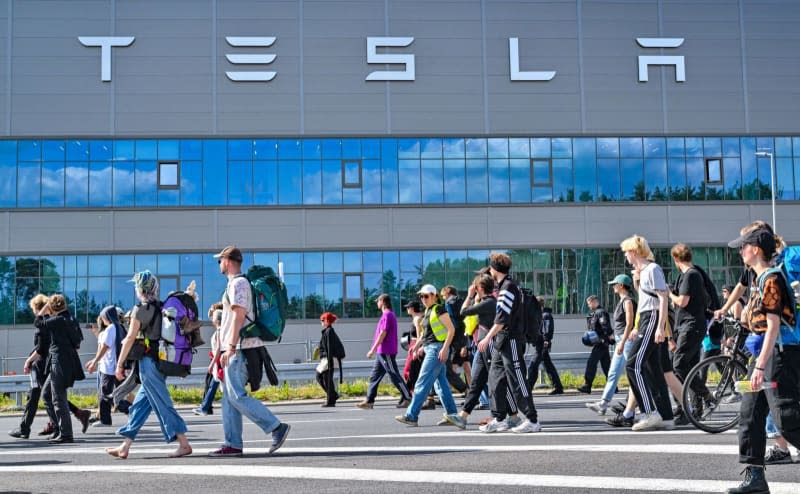 Environmental activists walk past the Tesla plant during a protest against Tesla. After sometimes violent clashes on May 10, 2024 at the Tesla factory site in Gruenheide near Berlin, new protests are currently underway against the US company. Patrick Pleul/dpa