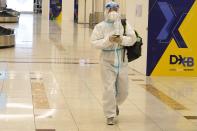 A passenger in a full, disposable hazmat suit arrives at the baggage claim area of Dubai International Airport's Terminal 3 in Dubai, United Arab Emirates, Thursday, Nov. 26, 2020. The low-cost carrier flyDubai began regular flights to Tel Aviv on Thursday, the latest sign of the normalization deal between the UAE and Israel. (AP Photo/Jon Gambrell)