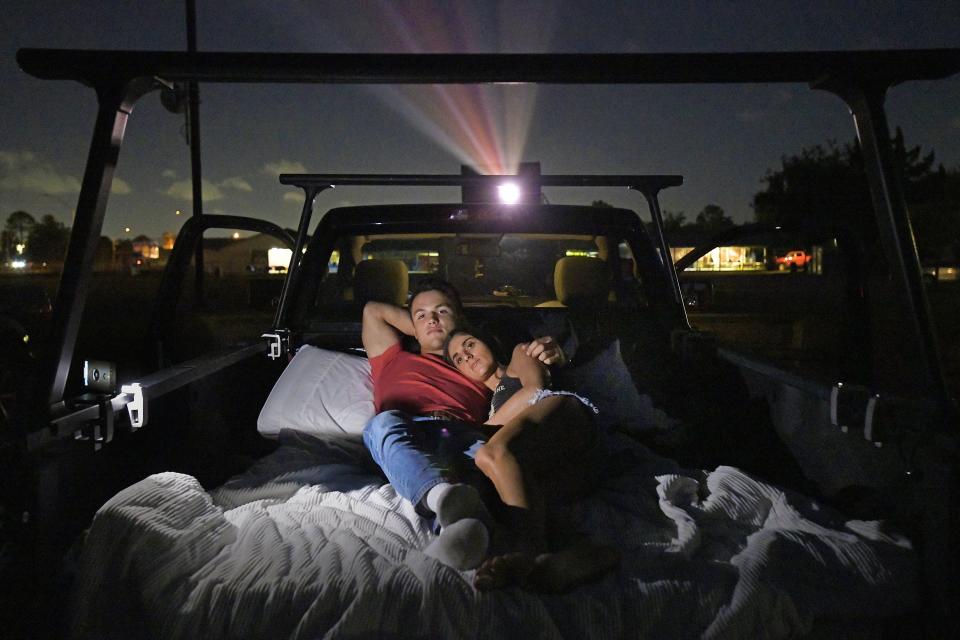 Some moviegoers at the Sun-Ray drive-in theater sit in their air-conditioned cars and watch the film through their windshield. Others, like Matthew Kuhlmann and Olivia Rawls, back into the spot, drop the tailgate and watch from the back of their vehicle.