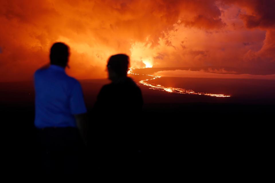 Spectators watch the lava flow down the mountain from the Mauna Loa eruption, Tuesday, Nov. 29, 2022, near Hilo, Hawaii (AP)