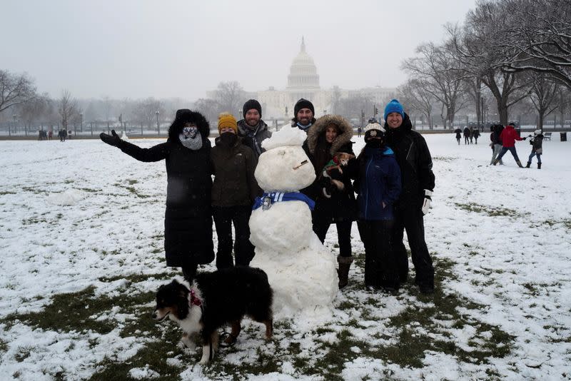 People pose for a picture next to a snowman at the National Mall in Washington