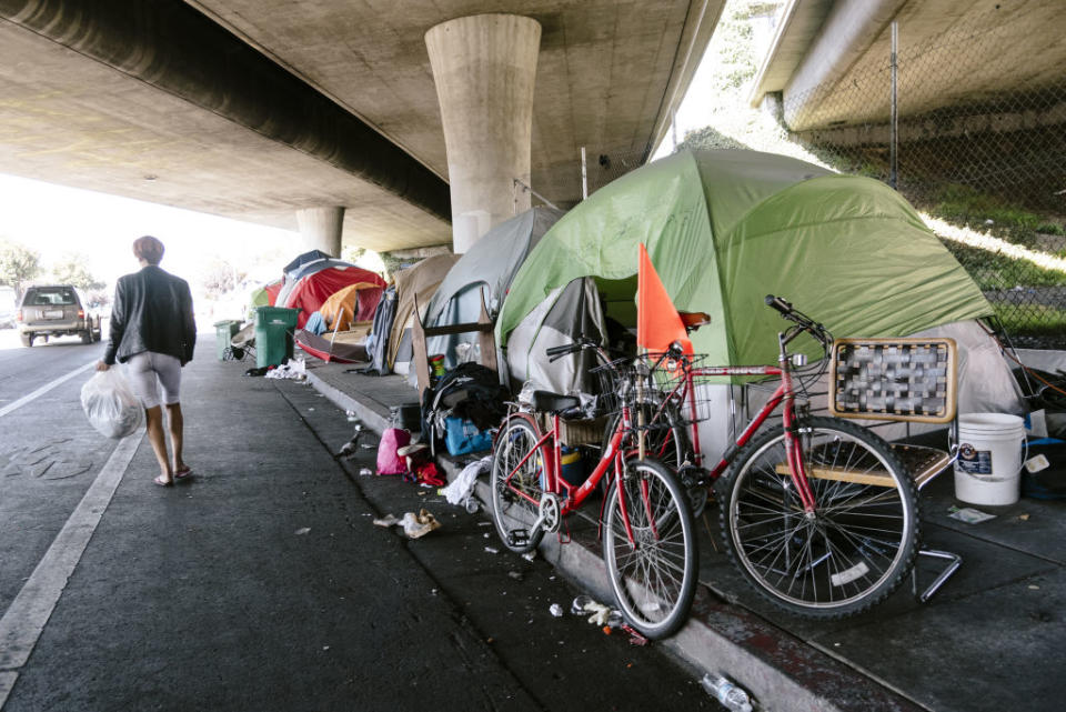 A person walks past a homeless encampment in Oakland, California,  on Friday, Aug. 30, 2019. | A person walks past a homeless encampment in Oakland, California, on Friday, Aug. 30, 2019.