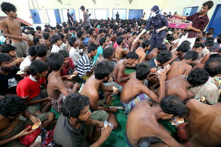 Malaysian police distribute bread to illegal immigrants from Bangladesh and Myanmar after they landed at Pantai Pasir Berdengung beach in Langkawi island, in the Malaysian northern state of Kedah, Malaysia, May 11, 2015. REUTERS/The New Straits Times Press/Amran Hamid