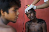 An Indonesian volunteer cuts the hair of a Bangladeshi migrant, who recently arrived in Indonesia by boat, at a shelter in Kuala Langsa, in Indonesia's Aceh Province, May 19, 2015. REUTERS/Beawiharta