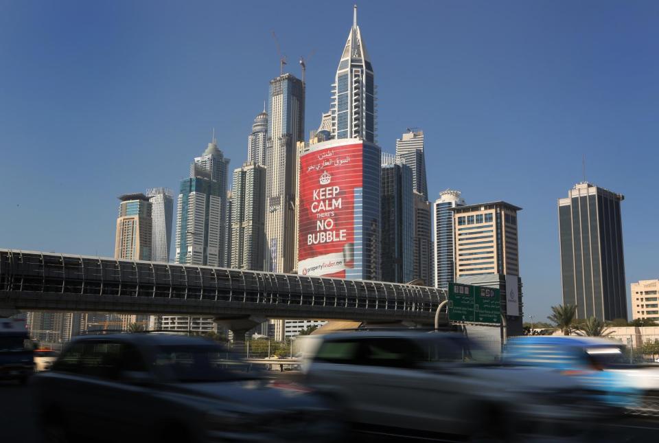 In this Wednesday Nov. 13, 2013 photo, vehicles pass by a tower with a sign that reads, "Keep Calm, No Bubble," at the Marina district in Dubai, United Arab Emirates. The logo for Dubai’s bid to host the Expo 2020 reflects a push by the city’s leaders to avert another financial crisis like the one that brought the city to its knees in 2008. Dubai saw property values slashed by more than half and the city’s government needed a $10 billion bailout from oil-rich neighbor Abu Dhabi in 2009. (AP Photo/Kamran Jebreili)
