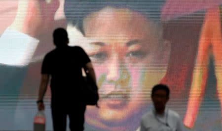 FILE PHOTO: Men walk past a street monitor showing news of North Korea's intercontinental ballistic missile test in Tokyo, Japan, July 4, 2017. REUTERS/Toru Hanai/File Photo