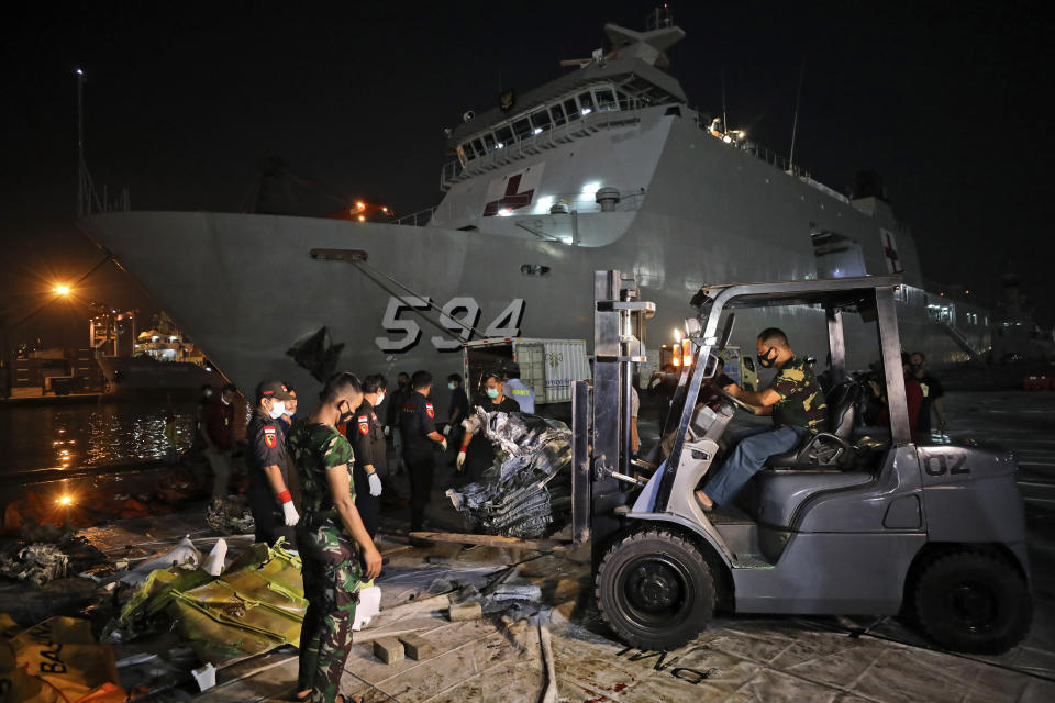 Workers remove parts of the wreckage of Sriwijaya Air flight SJ-182 that crashed into the Java Sea on Jan. 9, to be loaded onto a truck and transported for further investigation, at Tanjung Priok Port in Jakarta, Indonesia, Thursday, Jan. 21, 2021. Indonesian authorities on Thursday ended the search for the wreckage of the plane that nose-dived into the sea, killing all of its passengers on board. (AP Photo/Dita Alangkara)