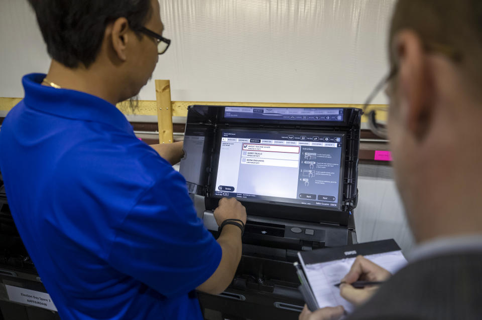 Torrance County administrative assistant clerk Kevin Pham, left, shows a ballot-counting machine to Libertarian Party county chairman Robert Wagner during a testing of election equipment in Estancia, N.M., Sept. 29, 2022. (AP Photo/Andres Leighton)