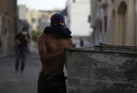 A Bahraini anti-government protester pushes a garbage bin to block a street during clashes with riot police in Sanabis, Bahrain, on the edge of the capital of Manama, Saturday, April 19, 2014. Clashes erupted during a march in the village over a dispute between relatives and authorities about the official cause of death for a 27-year-old man who died Thursday of injuries sustained in earlier clashes. Authorities in Bahrain say an apparent car bombing has killed two people and wounded one west of the capital, Manama. (AP Photo/Hasan Jamali)