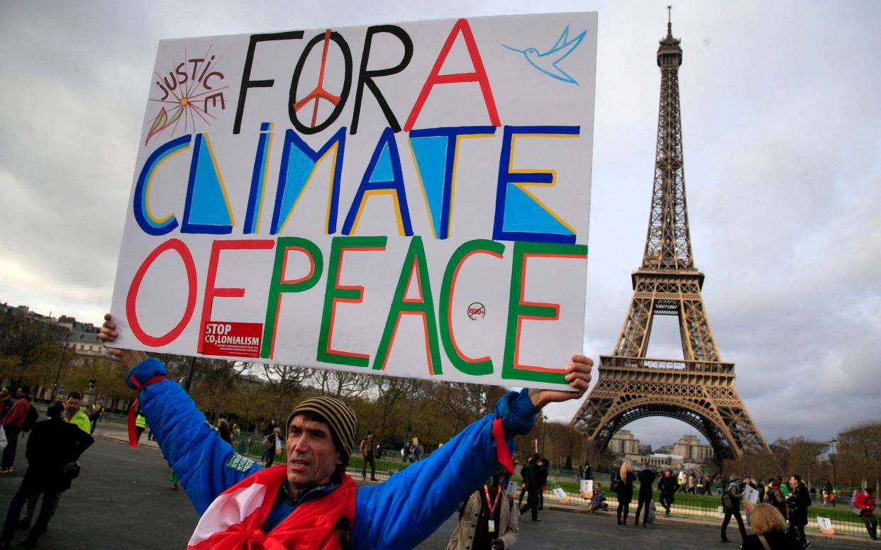 An activist holds a poster during a demonstration near the Eiffel Tower during the Paris COP21 meeting in 2015 - Thibault Camus /AP