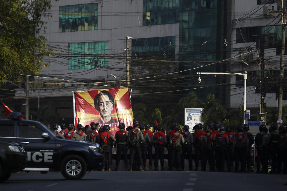 A large banner with an image of deposed Myanmar leader Aung San Suu Kyi faces rows of policemen blocking the road near the headquarters of the National League for Democracy party in Yangon, Myanmar Monday, Feb. 15, 2021. Security forces in Myanmar intensified their crackdown against anti-coup protesters on Monday, seeking to quell the large-scale demonstrations calling for the military junta that seized power earlier this month to reinstate the elected government. (AP Photo)