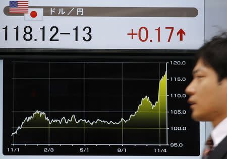 A man walks past an electronic board showing the Japanese yen's exchange rate against the U.S. dollar outside a brokerage in Tokyo November 20, 2014. REUTERS/Toru Hanai