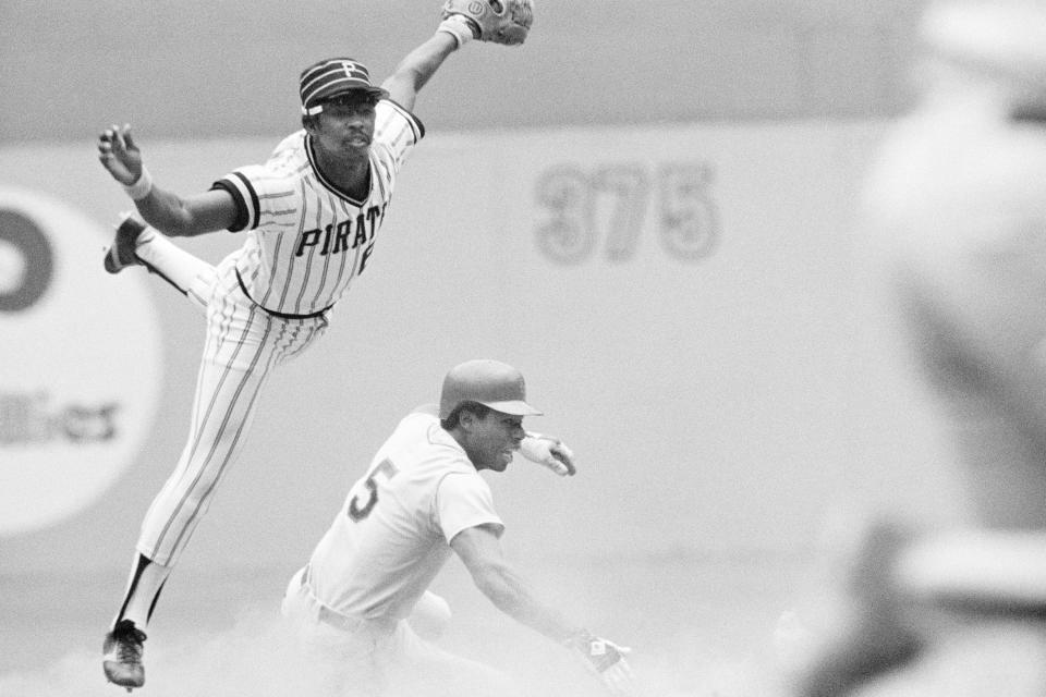 FILE - Pittsburgh Pirates second baseman Rennie Stennett leaps to try and avoid New York Mets' Steve Henderson sliding in trying to break up a double play during the fourth inning of a baseball game in Pittsburgh, in this Aug. 14, 1977, file photo. Stennett completed the double play to first base. Rennie Stennett has died. He was 72. The team, citing information provided by the Stennett family, said Stennett passed away early Tuesday morning, May 18, 2021, following a bout with cancer. (AP Photo/File)