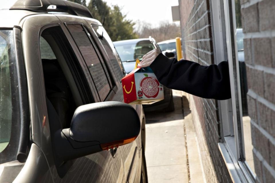 An employee hands a customer a happy meal at the drive-thru of a McDonald's Corp. restaurant in Peru, Illinois, U.S., on Wednesday, March 27, 2019. McDonald's, in its largest acquisition in 20 years, is buying a decision-logic technology company to better personalize menus in its digital push. Photographer: Daniel Acker/Bloomberg via Getty Images