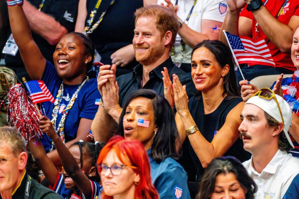 Prince Harry and Meghan Markle smile and clap