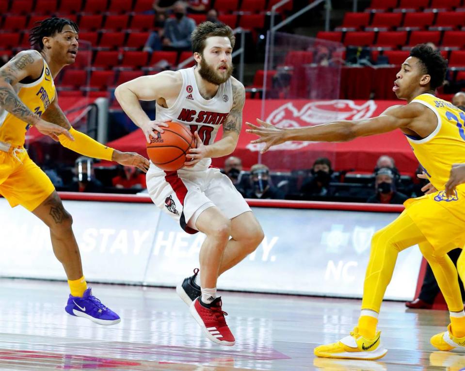 N.C. State’s Braxton Beverly (10) drives between Pittsburgh’s Nike Sibande (22) and William Jeffress (24) during the second half of N.C. State’s 65-62 victory over Pittsburgh at PNC Arena in Raleigh, N.C., Sunday, February 28, 2021.