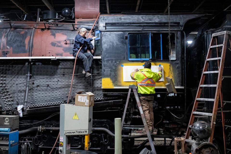 Volunteer Jean Kloha and master mechanic Justin Hamilton put masking tape on the Pere Marquette 1225 before a new paint job as they get ready for the first day of the North Pole Express at the Steam Railroading Institute in Owosso on Thursday, Nov. 16, 2023.