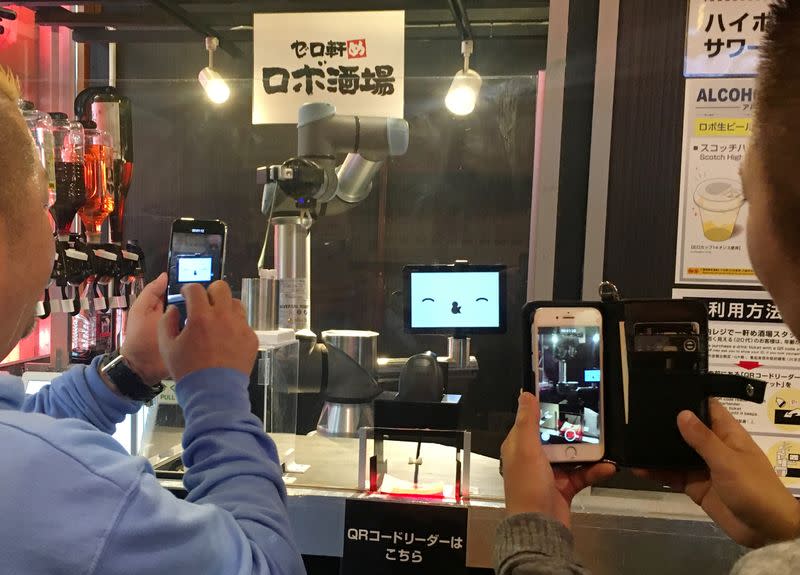 Customers take photos of a robot bartender at Japanese style bar Izakaya chain "Yoronotaki" in Tokyo