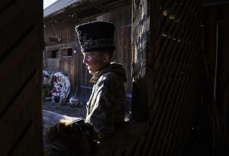 A participant, dressed in a traditional costume, leans on a windowsill while celebrating the Malanka festival in the village of Krasnoilsk, Ukraine, Friday, Jan. 14, 2022. Dressed as goats, bears, oxen and cranes, many Ukrainians rang in the new year last week in the colorful rituals of the Malanka holiday. Malanka, which draws on pagan folk tales, marks the new year according to the Julian calendar, meaning it falls on Jan. 13-14. In the festivities, celebrants go from house to house, where the dwellers offer them food. (AP Photo/Ethan Swope)