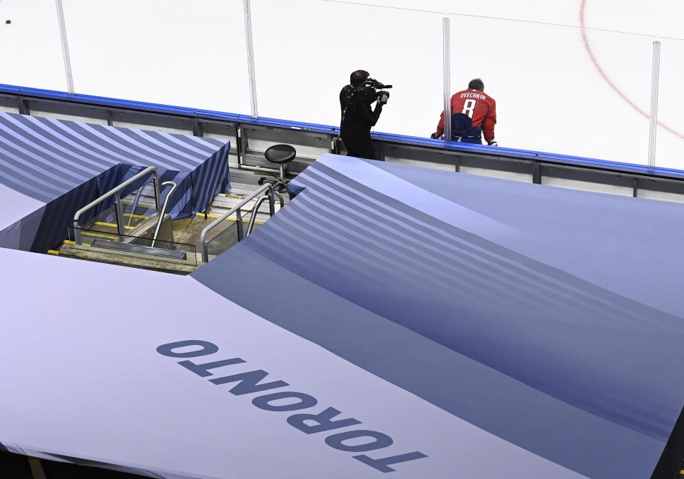 A television camera operator records Washington Capitals left wing Alex Ovechkin (8) prior to taking on the New York Islanders in NHL Eastern Conference Stanley Cup playoff hockey action in Toronto, Friday, Aug. 14, 2020. The NHL is providing its playoff teams a few tastes of home in their respective hub cities. Teams are hearing their pre-game warm-up music, goal songs and national anthem performers. Crowd noise is being piped in and new camera angles have been added for a TV audience. (Nathan Denette/The Canadian Press via AP)