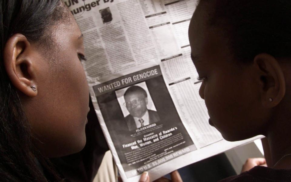 Readers look at a newspaper on June 12, 2002 in Nairobi carrying the photograph of Felicien Kabuga wanted by the United States - REUTERS