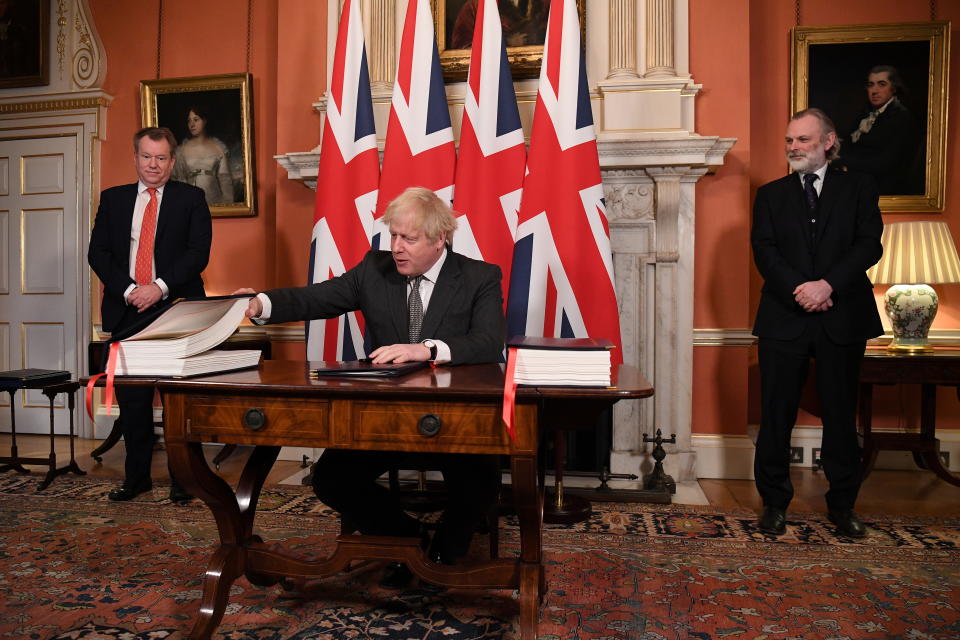 UK chief trade negotiator David Frost and British Ambassador to the EU Tim Barrow look on as Britain's Prime Minister Boris Johnson signs the Brexit trade deal with the EU at number 10 Downing Street in London, Britain December 30, 2020. Leon Neal/Pool via REUTERS