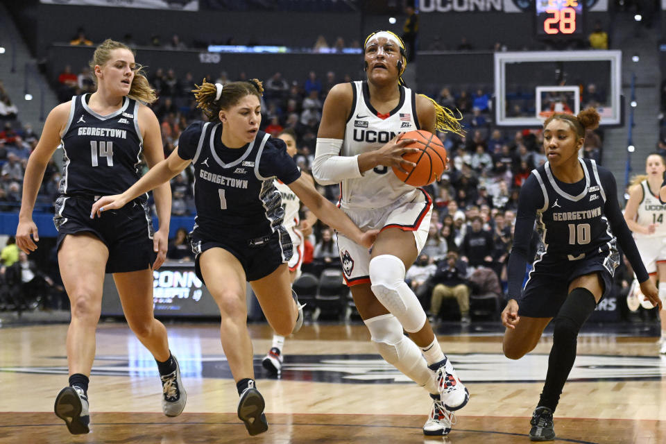 UConn's Aaliyah Edwards, second from right, advances to the basket after stealing the ball while pursued by Georgetown's Kristina Moore (14), Kelsey Ransom (1) and Kennedy Fauntleroy (10) in the second half of an NCAA college basketball game, Sunday, Jan. 15, 2023, in Hartford, Conn. (AP Photo/Jessica Hill)