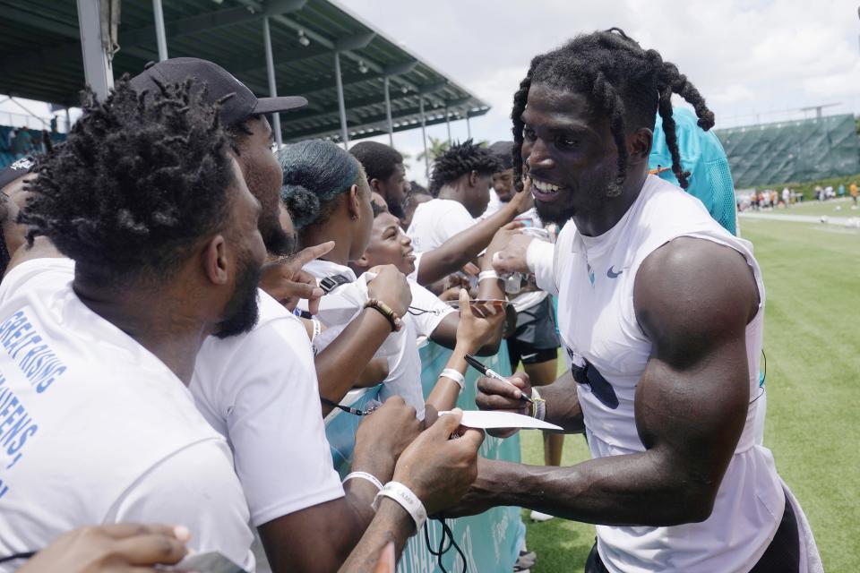 New Dolphins receiver Tyreek Hill signs autographs for fans after Saturday's practice, which he started with a back flip as he ran onto the field.